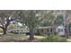 Exterior view of single-story house with covered parking, green lawn, and trees draped with spanish moss at 401 Sunny Ct, Fruitland Park, FL 34731