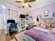 Bedroom with a ceiling fan, a work area, and purple walls filled with artwork and decorations at 4334 Tolkien St, Orlando, FL 32828