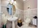 Stylish powder room with tiled walls, pedestal sink, round mirror, and decorative accents at 4334 Tolkien St, Orlando, FL 32828