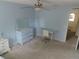 Light blue bedroom featuring a ceiling fan, desk, and a mirror with neutral colored carpeting at 4531 Se 30Th St, Ocala, FL 34480