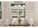 Bright dining area with rustic wood table, charming light fixtures, and a view of the outdoors at 5531 Marys Villa Rd, Groveland, FL 34736