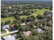 An aerial view showcases the neighborhood, with lush green trees, a golf course, and houses with pools at 636 Cheviot Ct, Apopka, FL 32712