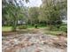 A wide shot of the home's backyard with mature trees and a stone patio at 636 Cheviot Ct, Apopka, FL 32712