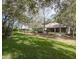 Backyard of home with lush landscaping, mature shade trees, and manicured lawn leading to screened patio at 636 Cheviot Ct, Apopka, FL 32712