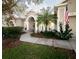Inviting front of house with lush landscaping, a paved walkway, and a charming arched entrance at 636 Cheviot Ct, Apopka, FL 32712