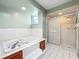Bathroom featuring a jacuzzi tub and glass-enclosed shower with tiled floors and walls at 6970 Knightswood Dr, Orlando, FL 32818