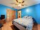Bedroom with blue walls, wood floors, ceiling fan, and view into bathroom at 6970 Knightswood Dr, Orlando, FL 32818