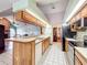 Functional kitchen featuring wood cabinets, white tile flooring, and a breakfast bar open to the living area at 6970 Knightswood Dr, Orlando, FL 32818