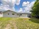 View of backyard with lawn and exterior of single story home with black roof, grey exterior and a patio at 7040 Hennepin Blvd, Orlando, FL 32818
