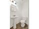 Clean, white bathroom featuring a pedestal sink and toilet with modern wood-look flooring at 7807 Pine Hawk Ln, Orlando, FL 32822