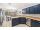 Bright kitchen featuring blue cabinets, stainless steel appliances, and dining area with pool view at 8308 Granada Blvd, Orlando, FL 32836