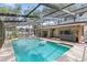 Inviting screened-in pool area with a spacious patio, hot tub, and lush landscaping at 8308 Granada Blvd, Orlando, FL 32836