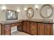 Bathroom with granite countertops, wood cabinets, stylish mirrors and modern vanity lighting at 991 Hawthorne Cove Ct, Ocoee, FL 34761