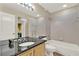 Well-lit bathroom featuring a granite countertop, and a tub with tiled surround at 991 Hawthorne Cove Ct, Ocoee, FL 34761