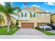 Two-story home featuring a two-car garage, a well-maintained lawn, and a charming palm tree in the front yard at 10070 Red Eagle Dr, Orlando, FL 32825