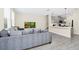 Open-concept living room flowing into kitchen, featuring gray sofa and wood-look tile flooring at 10070 Red Eagle Dr, Orlando, FL 32825