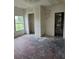 A bedroom featuring bare floors, a window view of the yard, and open closets at 1020 E Main St, Haines City, FL 33844