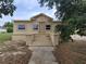Single-story home with concrete steps leading to the front door under a partly cloudy sky at 1020 E Main St, Haines City, FL 33844