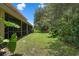 Overgrown backyard with lush greenery, lawn, and partially screened porch at 1434 Pacific Rd, Kissimmee, FL 34759
