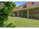View of a sunny backyard with a screened lanai and lush green grass at 1434 Pacific Rd, Kissimmee, FL 34759