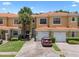 Inviting townhome exterior with a red tile roof, brick driveway, and lush landscaping, including a palm tree at 1434 Pacific Rd, Kissimmee, FL 34759