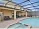 A covered pool area with an attached spa, lounge chairs, and an outdoor dining space at 1606 Lima Ave, Kissimmee, FL 34747