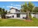 Picture of the fenced backyard with a patio, lawn, tropical trees, and sliding glass doors leading into the home at 1615 W Gadsen Blvd, Orlando, FL 32812