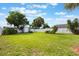 Spacious fenced backyard featuring a green lawn, tropical foliage, and providing ample space for outdoor activities at 1615 W Gadsen Blvd, Orlando, FL 32812