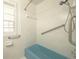 Close-up on blue bathtub in bathroom featuring a white tiled surround with grab bars and shower head at 1621 Sunnyside Dr, Maitland, FL 32751