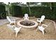 A cozy fire pit is surrounded by white Adirondack chairs and gravel, and a green hedge surrounds the yard at 1653 Cheyenne Trl, Maitland, FL 32751