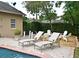 An in-ground pool has a lounge area with neutral colored lounge chairs surrounded by green hedges and trees at 1653 Cheyenne Trl, Maitland, FL 32751