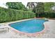 The in-ground pool is surrounded by a brick patio and has green hedges for privacy at 1653 Cheyenne Trl, Maitland, FL 32751