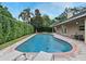The in-ground pool features a brick surround, poolside seating, and green hedges for privacy at 1653 Cheyenne Trl, Maitland, FL 32751