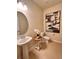 Cozy powder room featuring pedestal sink, modern fixtures, toilet, and contemporary wall art at 17319 Million Lakes Ct, Clermont, FL 34714