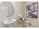 Stylish half bathroom with a modern vanity, oval mirror, decorative artwork and clean white toilet at 17319 Million Lakes Ct, Clermont, FL 34714