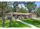 Charming single-story home featuring a brick facade, lush green lawn, and mature trees under a bright, sunny sky at 203 N Sweetwater Blvd, Longwood, FL 32779