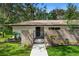 Charming front yard featuring a brick facade, iron gate, walkway, and well-manicured landscaping with various plants at 203 N Sweetwater Blvd, Longwood, FL 32779