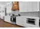 Bright kitchen with white cabinets, geometric backsplash, stainless-steel appliances, and wood flooring at 27071 Moss View Dr, Tavares, FL 32778