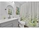 Bright bathroom featuring a modern vanity, round mirror and a floral shower curtain at 3043 Mapleshade St, Deltona, FL 32738