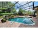 Backyard screened-in pool with waterfall, lush landscaping, and brick paver patio at 3102 Cecelia Dr, Apopka, FL 32703