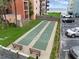 Outdoor shuffleboard court with benches, beach grass, and parked cars on a bright sunny day at 4141 S Atlantic Ave # 707, New Smyrna Beach, FL 32169