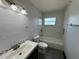 This bathroom has white tile, toilet and gray vanity with white sink at 4534 Lemans Dr, Orlando, FL 32808