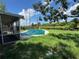 Backyard pool with a green safety cover with power lines overhead surrounded by sparse grass and an open sky at 4534 Lemans Dr, Orlando, FL 32808