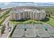 An aerial view showcases a beachfront condo with tennis courts, lush landscaping, and ocean views at 4650 Links Village Dr # B103, Ponce Inlet, FL 32127