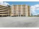 Exterior view of the building with large parking lot and lush landscaping at 4650 Links Village Dr # B103, Ponce Inlet, FL 32127