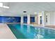 An indoor swimming pool features a blue mural, columns, and tile accents for a relaxing atmosphere at 4650 Links Village Dr # B103, Ponce Inlet, FL 32127