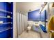 Vibrant bathroom with blue walls, a white toilet, and a tiled shower with striped curtain at 6310 Lake Underhill Rd, Orlando, FL 32807