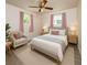 Cozy bedroom featuring a ceiling fan, stylish furniture, and natural light from two windows with pink curtains at 6310 Lake Underhill Rd, Orlando, FL 32807
