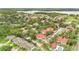 A wide aerial view of the neighborhood showcasing red roofs, mature trees, and nearby lake at 900 Northern Dancer Way # 204, Casselberry, FL 32707