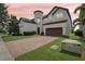 Charming two-story stucco home featuring a tile roof, brick driveway, and manicured lawn at sunset at 9207 Busaco Park Way, Winter Garden, FL 34787
